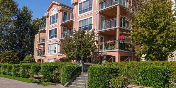 A peach-colored apartment building with balconies and greenery.