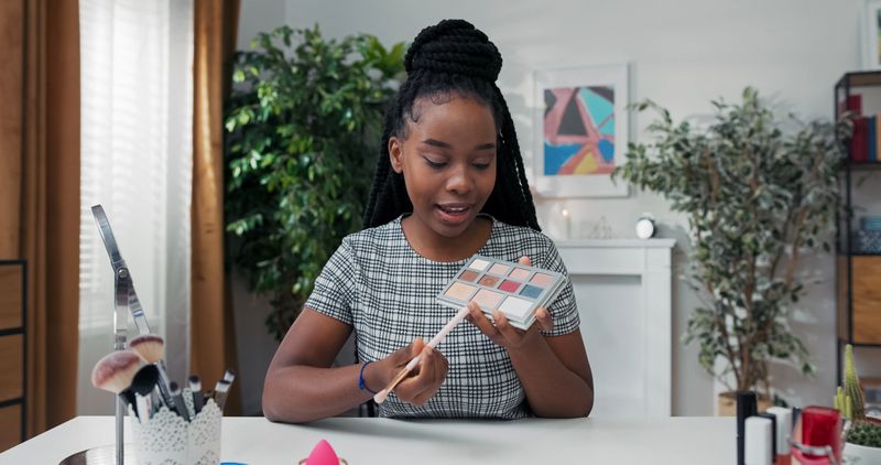 Focused close-up on a woman applying foundation with a sponge. She shares tips on achieving a flawless base before starting an eyeshadow blending tutorial for natural beauty.