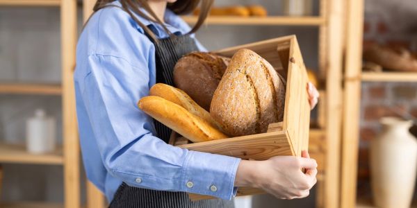 Person holding a crate of assorted bread.