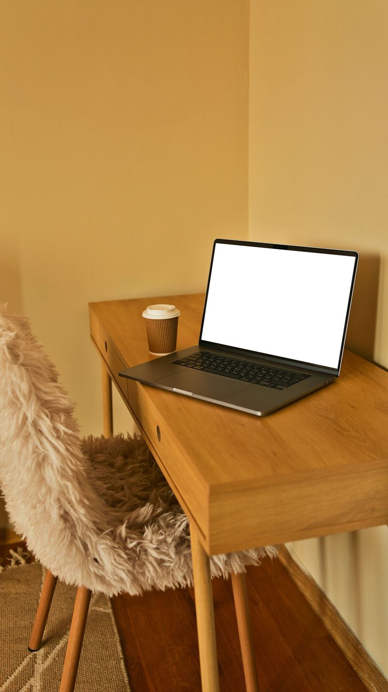A comfortable and inviting workspace featuring a plush chair, a minimalist wooden desk, and a laptop ready for productivity