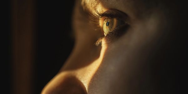 Close-up of a person's eye reflecting light in a dark setting.