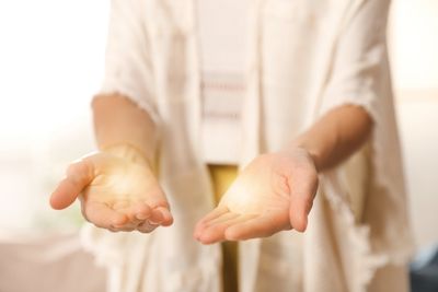Person holding glowing orbs of light in open hands.