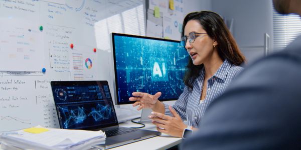 Woman explaining AI data and analytics on computer screens.