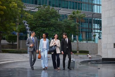 Four businesspeople walking and chatting outside an office building.