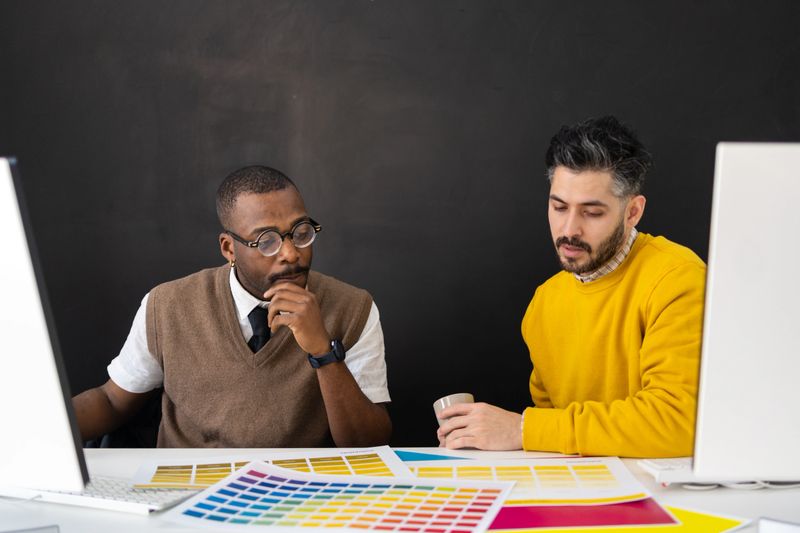 Graphic designers collaborating on a color branding project, reviewing swatches and choosing hues for creative development