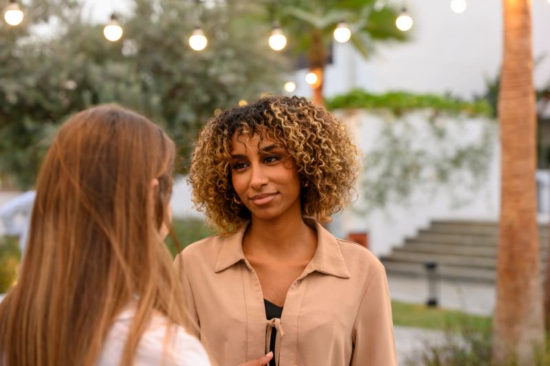 Two people are seen interacting outdoors with string lights illuminating the background, sharing a deep conversation and expressing emotional connection