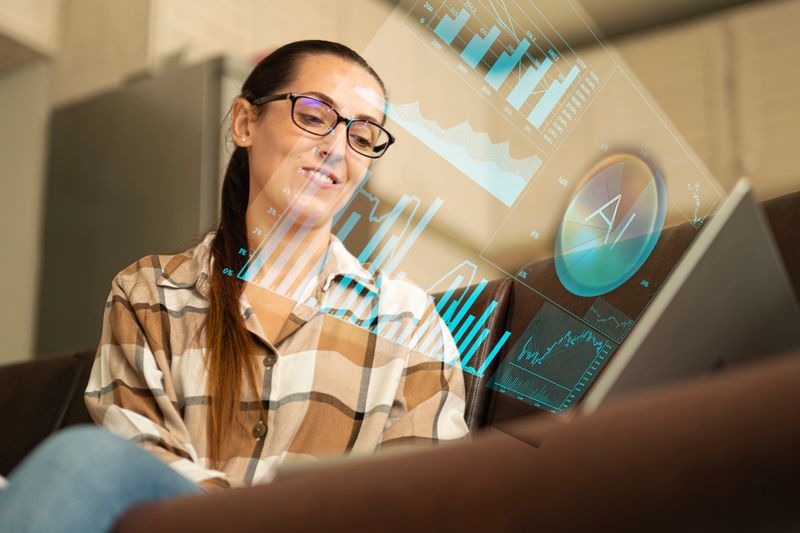 Business solutions concept. Business woman working on laptop, viewing hologram with AI data & financial graphs. Future technology, strategy & data optimization