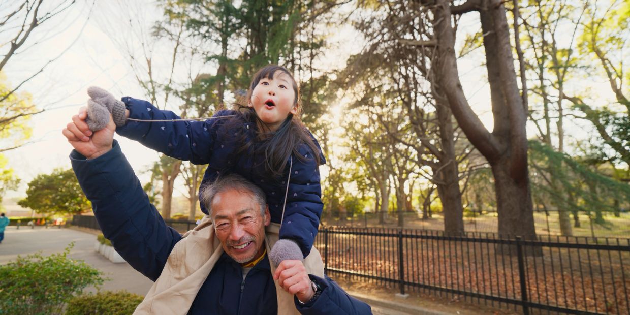 Kid riding on her grandpa's shoulders