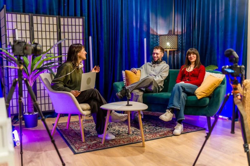 Three adults collaborating on a podcast, recording an interview in a vibrant studio setup with professional equipment, creating engaging digital content