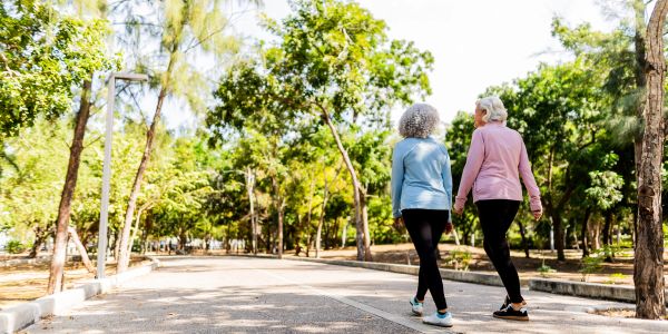 Two elderly women walking together in a park.