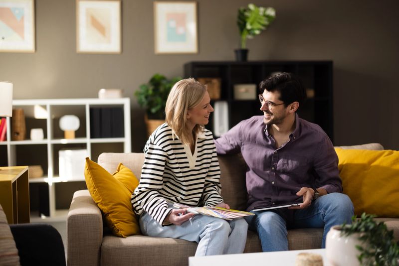 Smiling couple discusses design choices with color swatches and a digital tablet at home