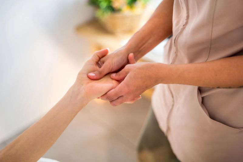 Professional woman therapist giving a relaxing hand massage and reflexology treatment to a female client during a wellness and self-care session, promoting stress relief and comfort