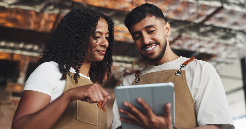 Waiter, teamwork and people with tablet in coffee shop for barista training, counting stock or inventory management. Hospitality industry, discussion and digital tech for cafe system or order help