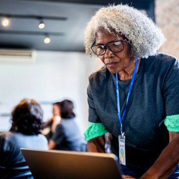 Older woman working on a laptop in a classroom.