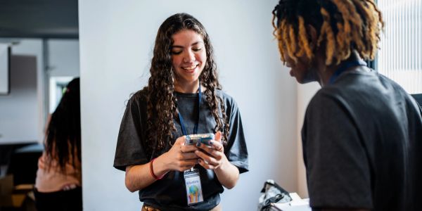 Two people interacting, one smiling at a phone.