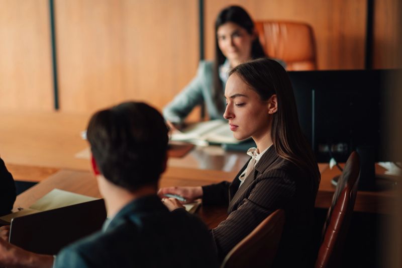 Professional women and men collaborating during an important business meeting or legal hearing in a corporate environment