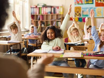 Élèves qui lèvent la main en classe