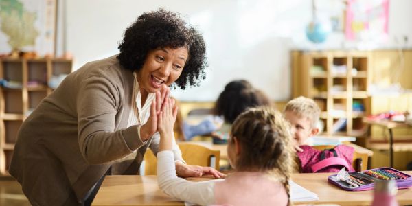 Teacher giving a high five to a student in classroom.