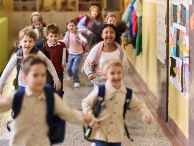 Kids excitedly running down a school hallway.