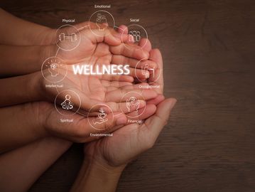 Hands holding the word 'WELLNESS' surrounded by health aspects icons.