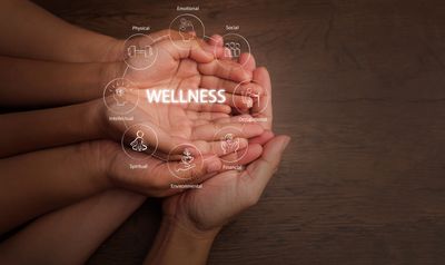 Hands holding icons representing different aspects of wellness.