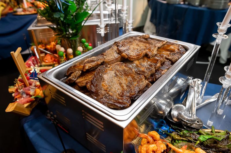 Grilled meats at the banquet. Tender grilled meats are beautifully arranged at an upscale banquet, surrounded by fresh garnishes and appetizers.