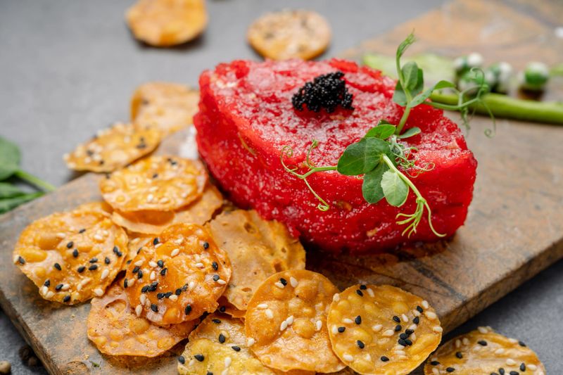 Red beet tartare with black caviar and crispy sesame chips served on stone board