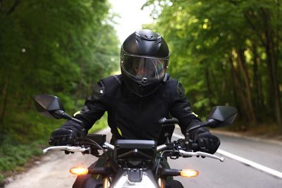 A motorcyclist riding on a tree-lined road