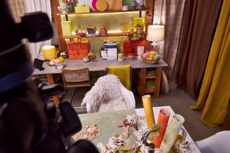 Cozy creative workshop interior prepared for filming online master classes and blog content, stylish craft studio with sewing machine, shelves, warm lighting, handmade decor, and camera in foreground. Concept of small creative business, DIY blogging, home studio production, entrepreneurship and artistic workspace