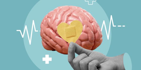 Hand holding a heart-shaped bandage on a brain model symbolizing mental health care.