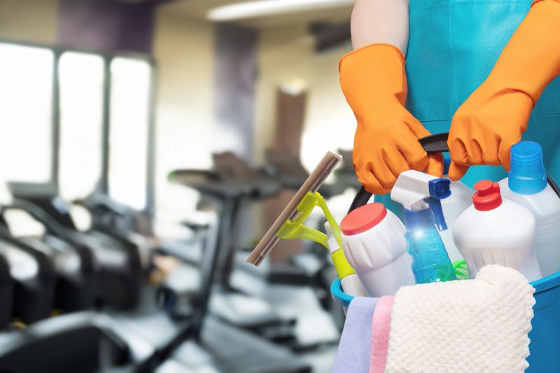 Keeping the gym spotless . A cleaner prepares to sanitize gym equipment in a bright fitness center.