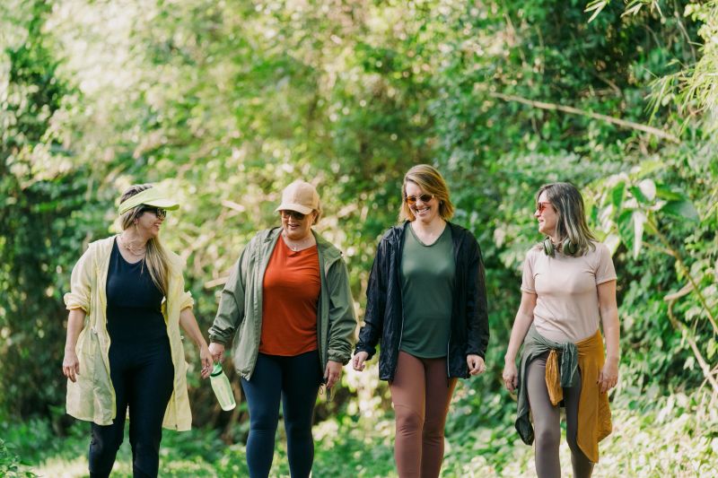 Group of women friends walking side by side on a nature trail during a casual outdoor hike.