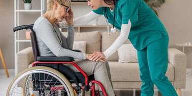 Nurse comforting a distressed elderly woman in a wheelchair at home.