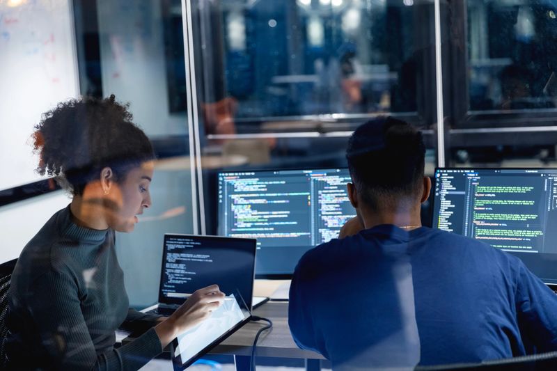 A diverse team of developers collaborates late into the night, developing secure code and patching vulnerabilities. Their focus on risk mitigation ensures a stable, high-quality product that aligns with client expectations.