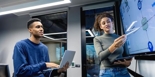 Two professionals collaborating with digital data on a transparent screen.