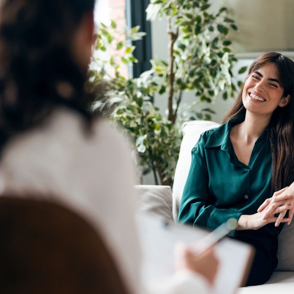 Woman happily talking to a therapist in a cozy room.