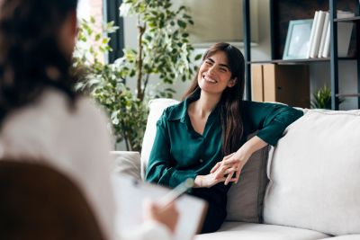 Woman smiling and talking on a couch.