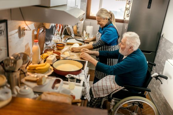 Couple cooking together in a kitchen with the man in a wheelchair.