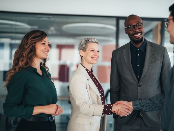 Business professionals smiling and shaking hands in a modern office.