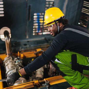Trabajador con casco amarillo realizando mantenimiento industrial.