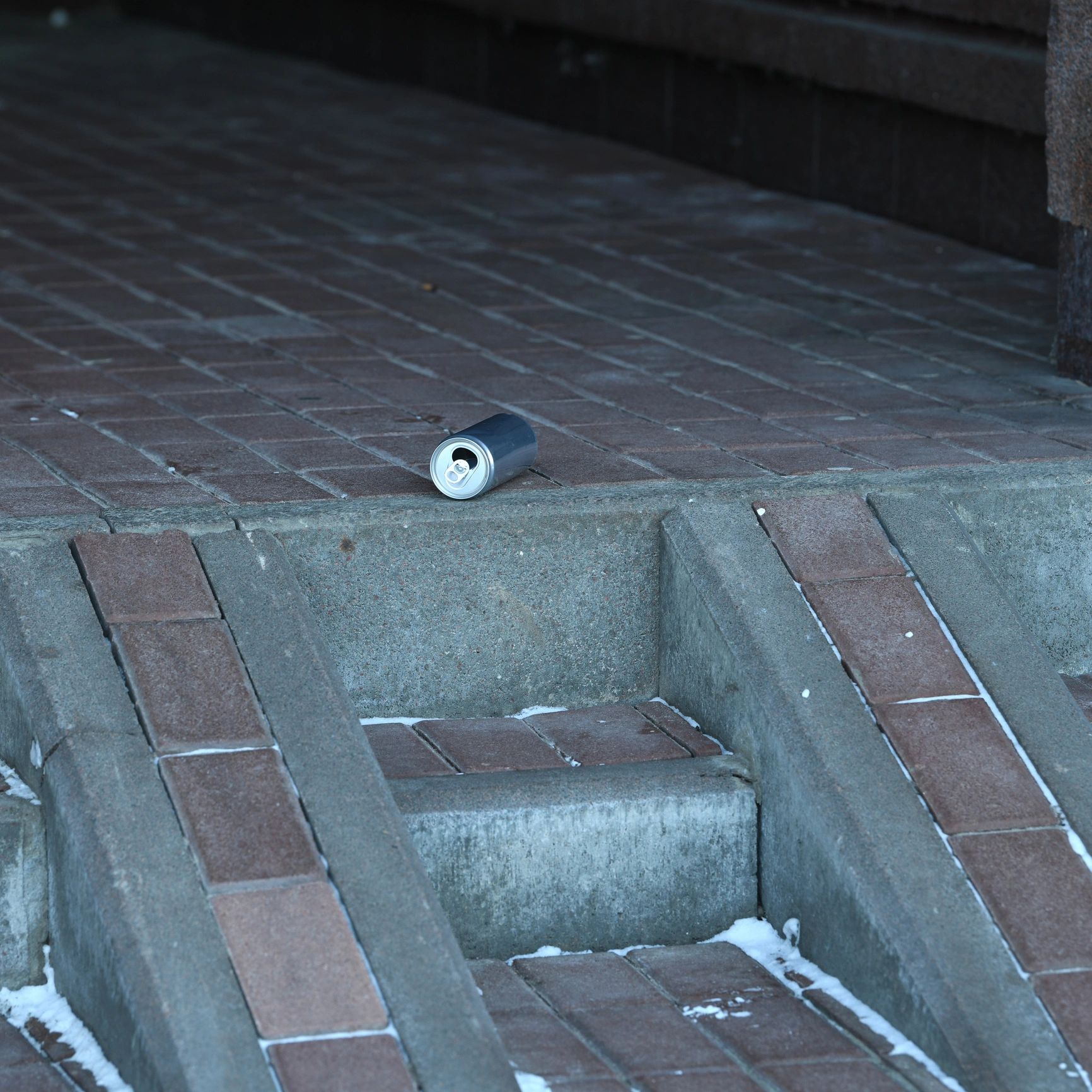 An empty can on a pavement corner.