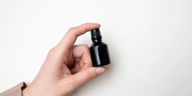 Hand holding a small black dropper bottle.
