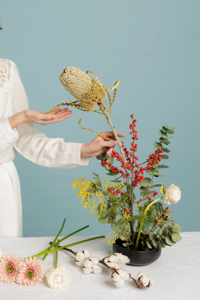 Florist presenting sculptural ikebana composition using kenzan with dried and fresh botanicals. Ideal for floristry branding, decor promotion, and lifestyle marketing campaigns.