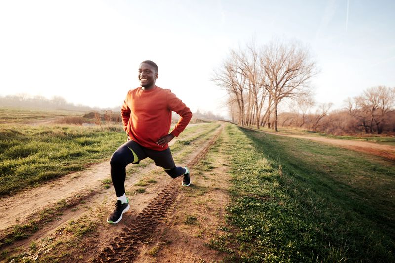 A young man stretches and warms up outdoors before a run, preparing his body for exercise and enjoying a healthy, active lifestyle in a natural setting.