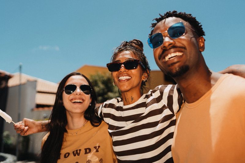 Young group of friends laughing together wearing sunglasses.