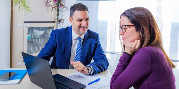 Businessman and woman discussing work at a desk with a laptop.