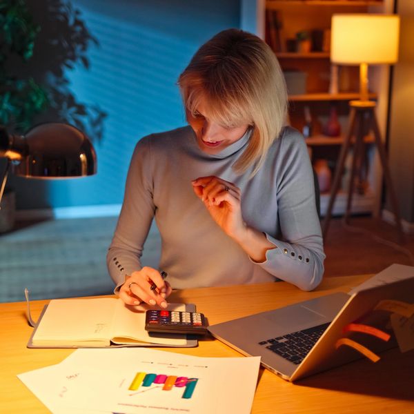 Woman calculating finances using a calculator at her desk.