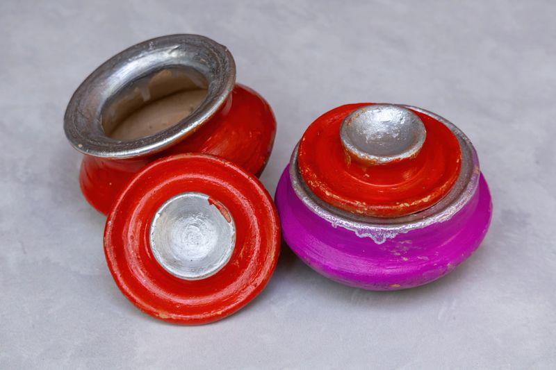 A vibrant group of miniature handcrafted painted clay pots with lids. Traditional colorful terracotta pottery and artisanal decorative containers for home decor, festivals, and cultural heritage