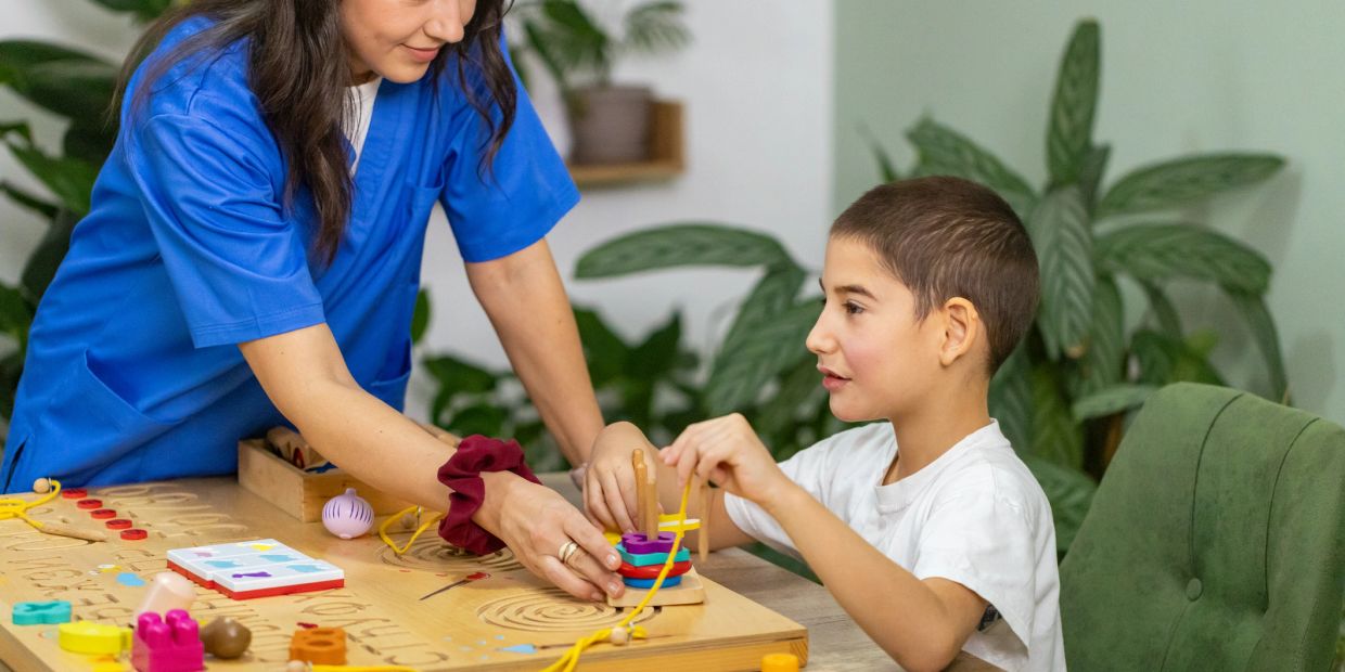 Therapist helping a child with a stacking toy.