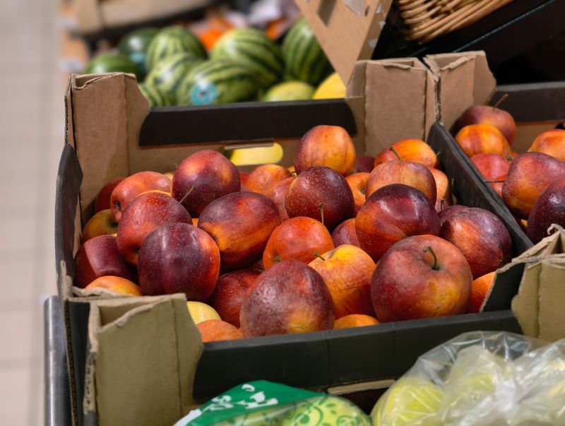 A close-up view of ripe red apples arranged in open cardboard boxes, ready for sale in a supermarket aisle